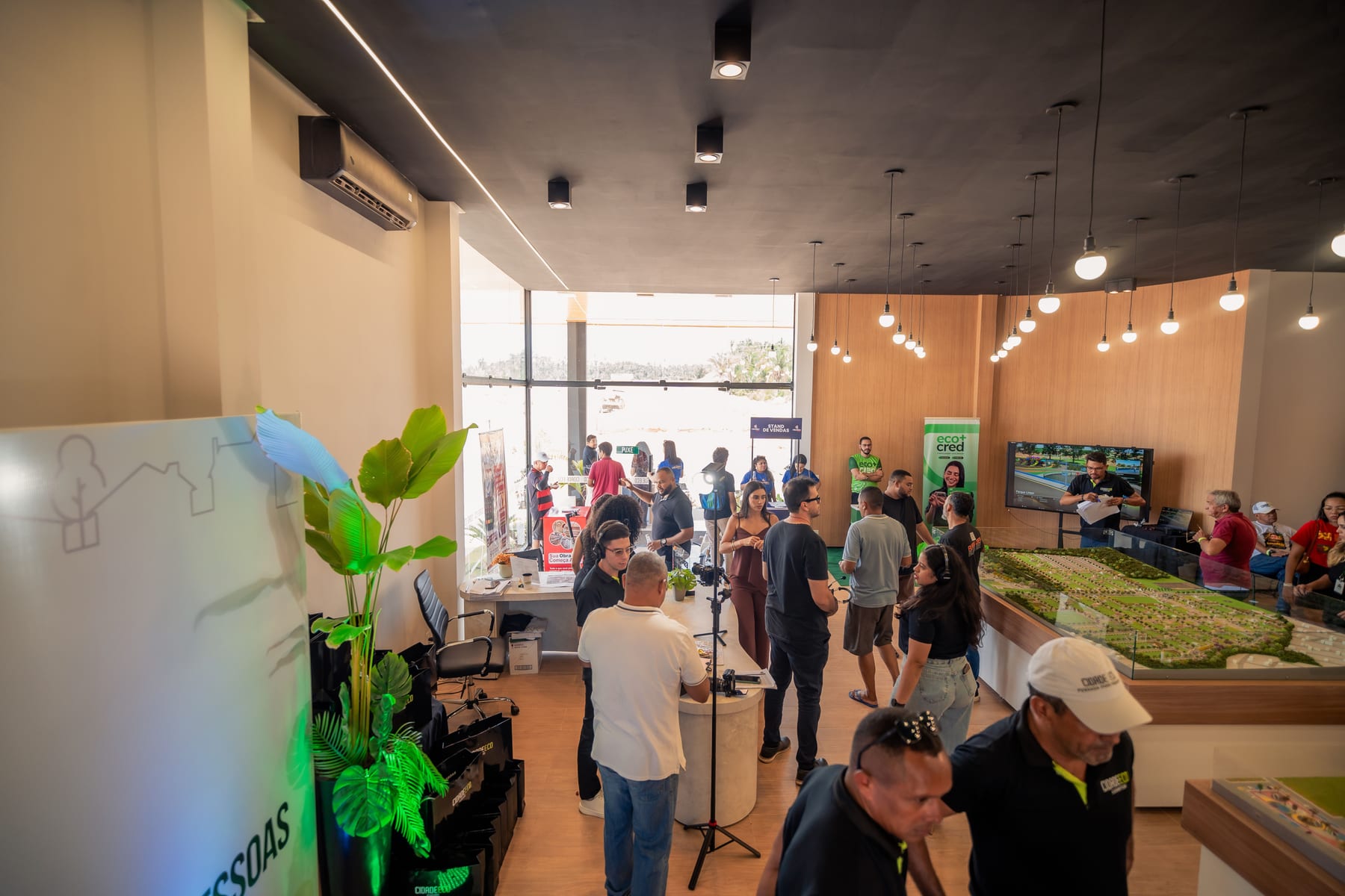 Foto do salão de um stand da Cidade Eco cheio de visitantes conversando com a equipe